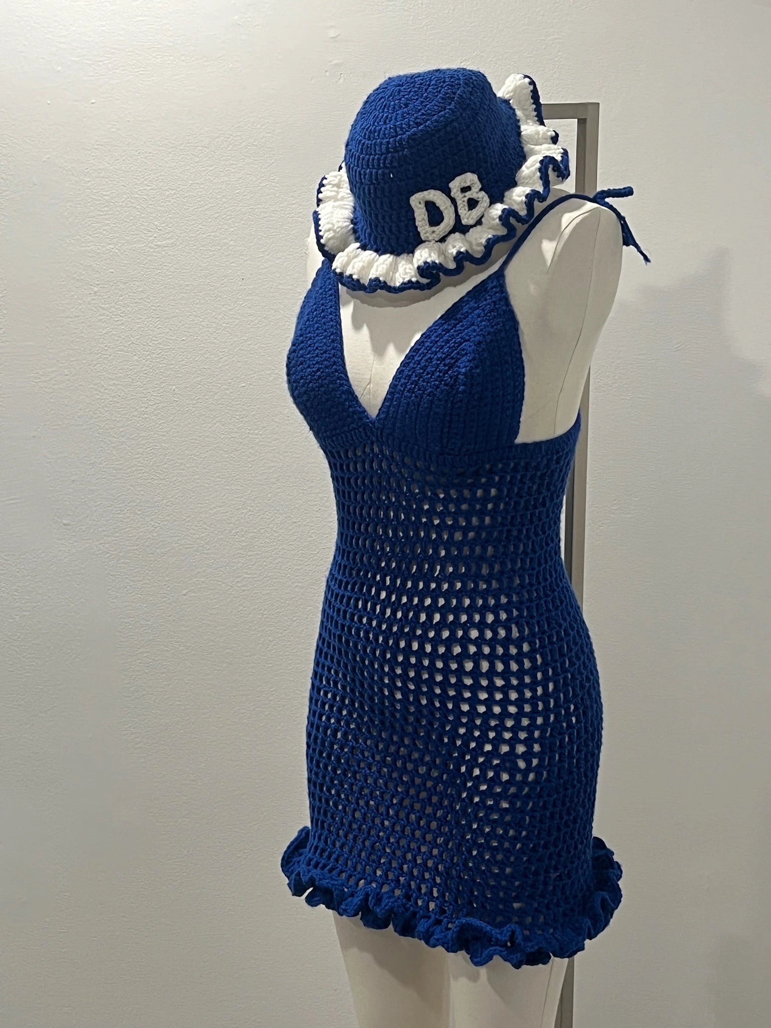 Blue crochet dress and matching headscarf on a mannequin against a plain background